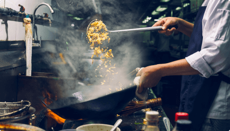 back view of wok cooking over stovetop